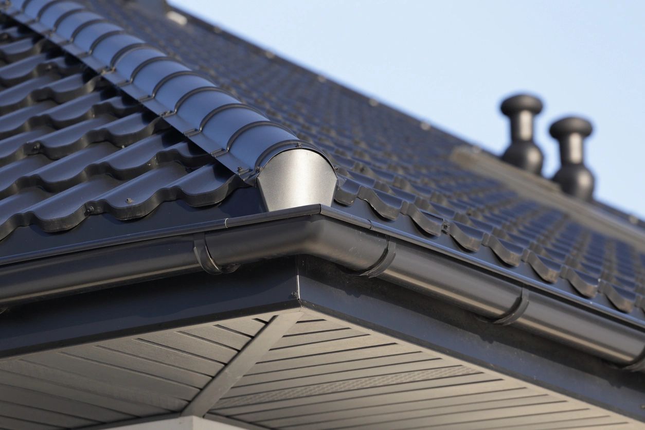 Residential roof corner with dark tiles and gutter