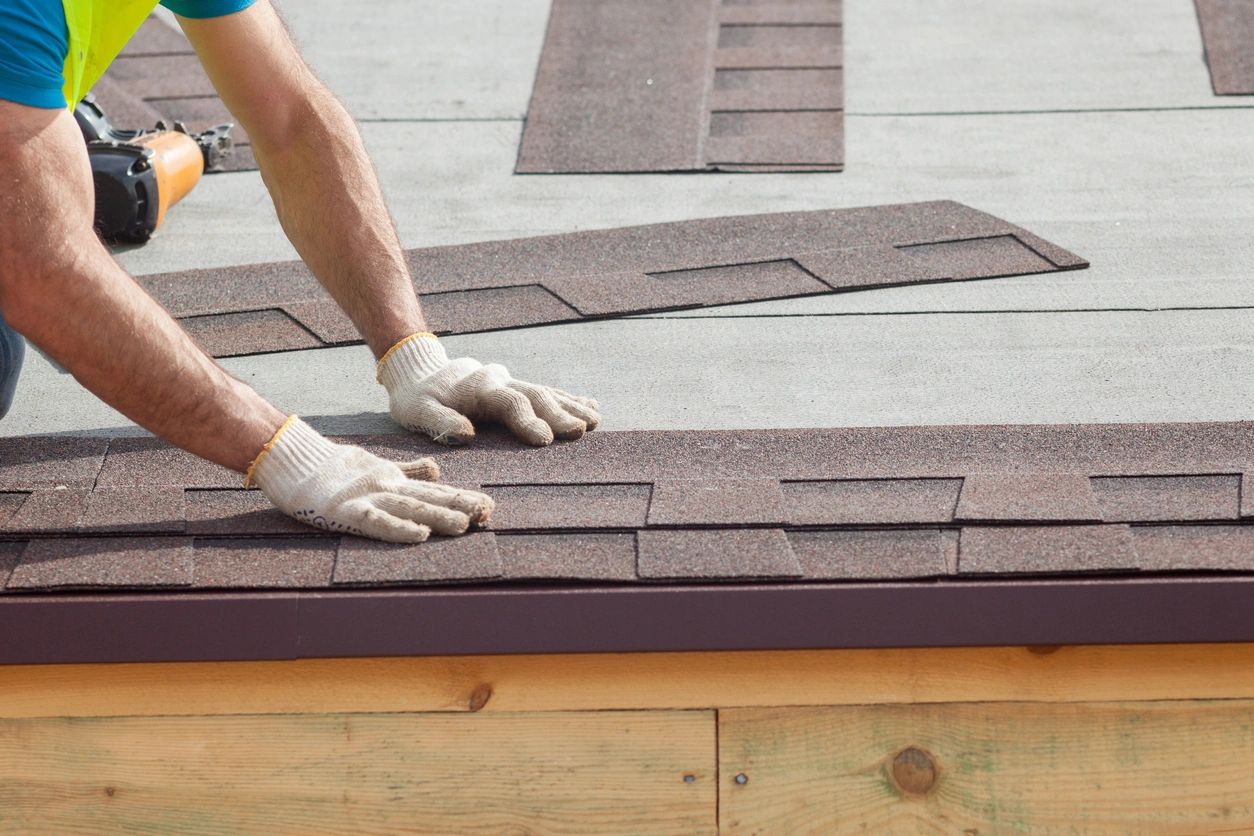 Worker installing shingles with nail gun